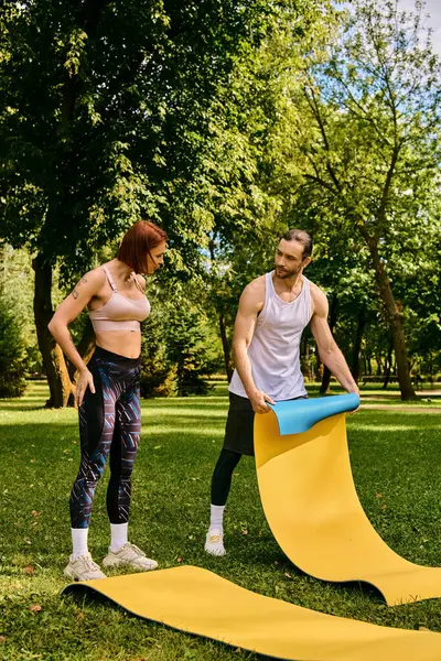Un hombre y una mujer en ropa deportiva disfrutan de un momento lúdico en un tobogán en un parque, lleno de determinación y motivación. - foto de stock