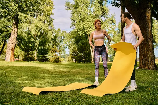 Un uomo e una donna determinati, in abbigliamento sportivo, stare accanto a un tappeto fitness giallo brillante, pronti a conquistare il loro allenamento — Foto stock