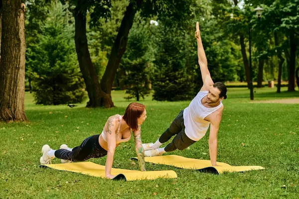 A man and woman in sportswear performing yoga poses in a serene park setting. — Stock Photo