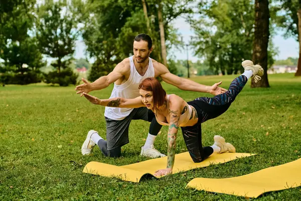 Una mujer en ropa deportiva practica yoga al aire libre con determinación y motivación, guiada por un entrenador personal. - foto de stock
