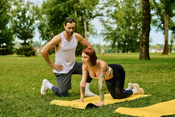 Un hombre y una mujer en ropa deportiva participan en flexiones, mostrando determinación y motivación mientras hacen ejercicio al aire libre - foto de stock