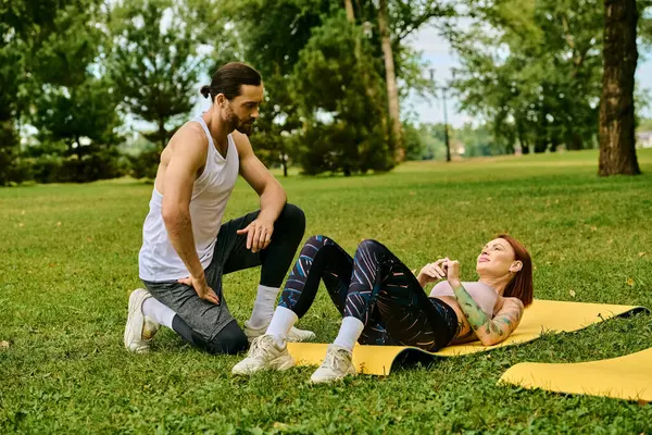 Uma mulher sportswear em um tapete amarelo ao ar livre, guiado por seu personal trainer em uma sessão de ioga cheia de determinação e motivação. — Fotografia de Stock