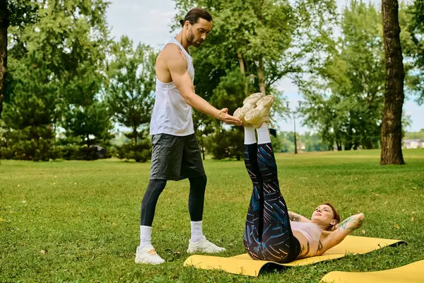 Une femme en tenue de sport effectue en toute confiance un portage sur un tapis dans un parc luxuriant, mettant en valeur la force et l'équilibre. — Photo de stock
