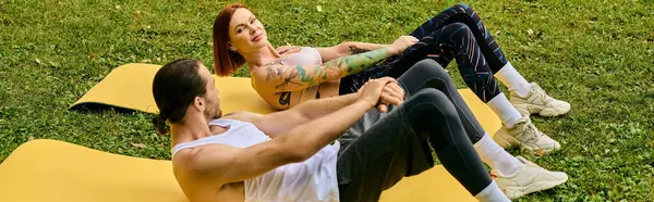 Un homme et une femme, vêtus de vêtements de sport, se livrent à divers exercices sur un tapis jaune vif à l'extérieur. — Photo de stock