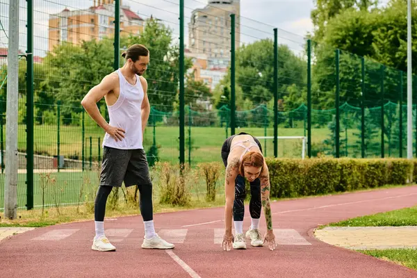 A man standing next to a woman on court, engaging in exercise and companionship on a sunny day. — Stock Photo