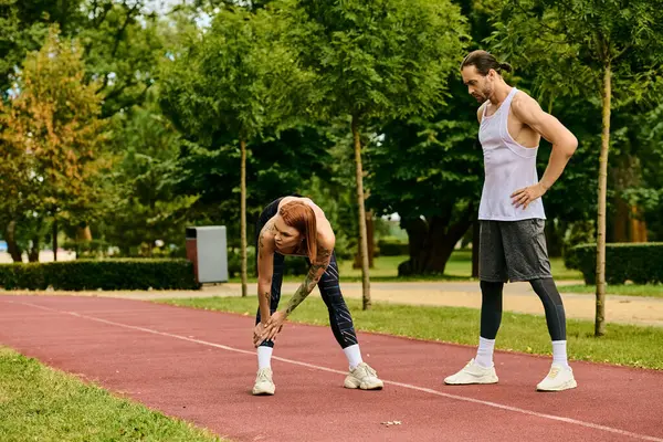 Un homme et une femme en tenue de sport se tiennent sur une piste, exerçant ensemble avec détermination et motivation. — Photo de stock