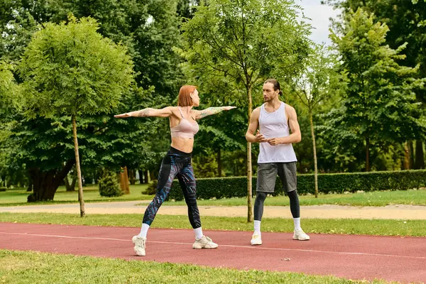 Un hombre y una mujer en ropa deportiva estirándose al aire libre, mostrando motivación. - foto de stock