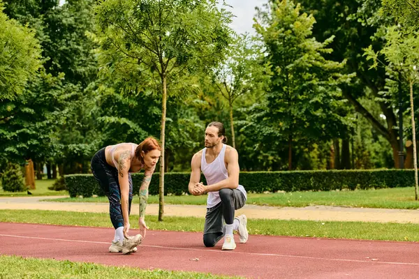 Une femme en tenue de sport s'entraîne dans l'herbe avec un entraîneur personnel, faisant preuve de détermination et de motivation. — Photo de stock