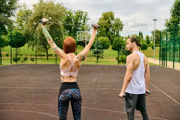 Un uomo e una donna in abbigliamento sportivo, guidati da un personal trainer, stanno su un campo con determinazione e motivazione.. — Foto stock