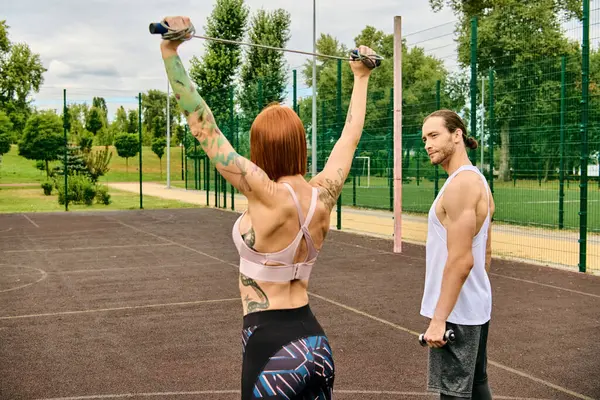 A man and a woman in sportswear are standing on a court, ready to practice under the guidance of their personal trainer. — Stock Photo