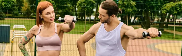 Un hombre y una mujer, usando ropa deportiva, participan en una sesión de entrenamiento en una vibrante cancha de tenis. - foto de stock