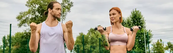 Man and woman in sportswear stand together outdoors, exercising with dumbbells — Stock Photo