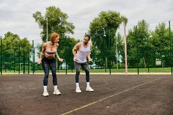 Dos mujeres atléticas en ropa deportiva se paran con confianza en la parte superior de una cancha de tenis, mostrando determinación y motivación. - foto de stock