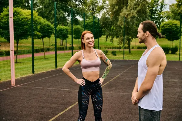 Um homem e uma mulher de sportswear estão prontos em uma quadra de tênis, mostrando determinação e motivação com seu personal trainer.. — Fotografia de Stock