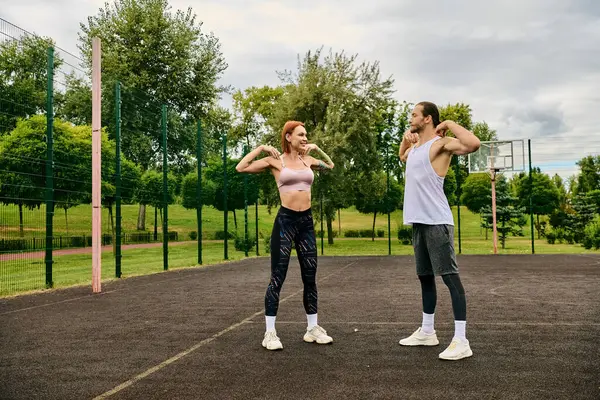 Una donna in abbigliamento sportivo stare in piedi su un campo, esercitando insieme con un personal trainer, mostrando determinazione e motivazione. — Foto stock