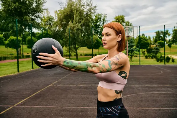 A woman in sportswear, holding a ball, trains outdoors with determination and motivation — Stock Photo