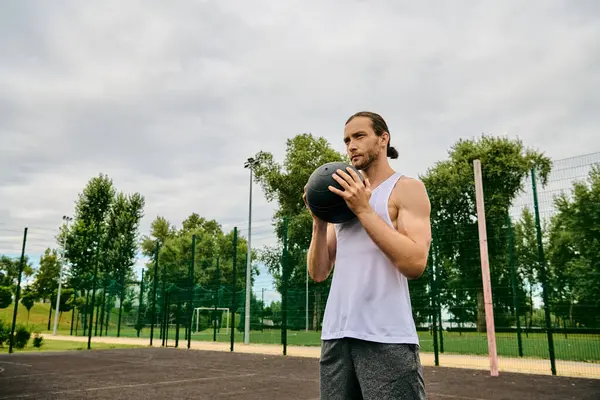 Un homme en tenue de sport tient une balle sur le terrain, faisant preuve de détermination et de motivation pour le match à venir. — Photo de stock