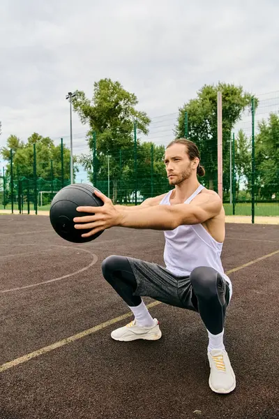 Ein Mann in Sportbekleidung hält einen Ball auf einem Platz und zeigt Entschlossenheit und Motivation bei seinem Workout. — Stockfoto