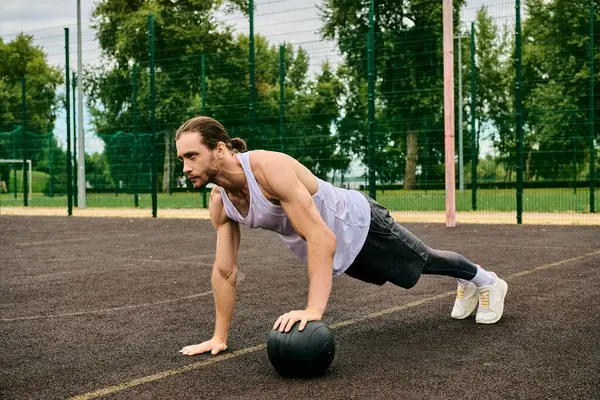 Un uomo in abbigliamento sportivo che esegue flessioni con una palla sotto la guida di un personal trainer, mostrando determinazione e motivazione. — Foto stock