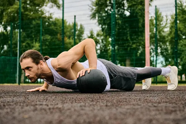 A man in sportswear performs push ups on the ground with determination as a personal trainer coaches him outdoors. — Stock Photo
