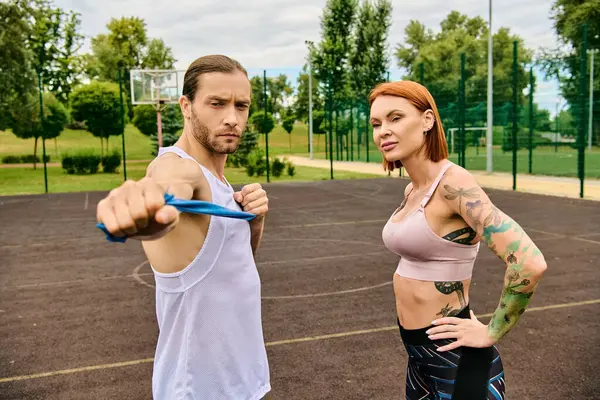 A man and woman in sportswear stand confidently on a court, displaying determination and motivation. — Stock Photo