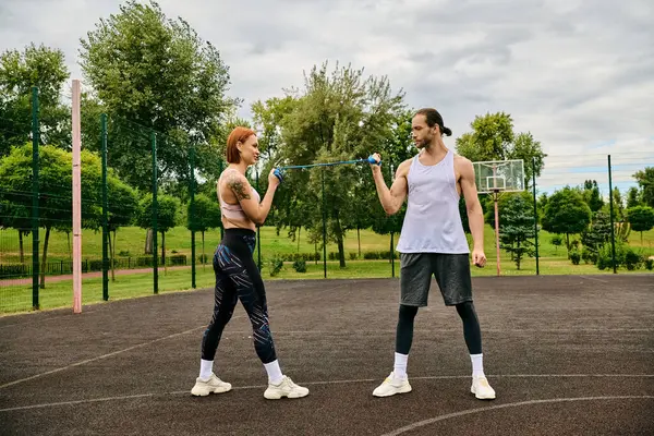 Um personal trainer dedicado e uma mulher determinada em sportswear estão resolutamente em um tribunal, incorporando motivação. — Fotografia de Stock