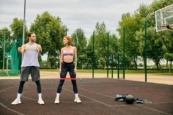 Un uomo e una donna in abbigliamento sportivo si allenano in un tribunale mostrando determinazione e motivazione. — Foto stock