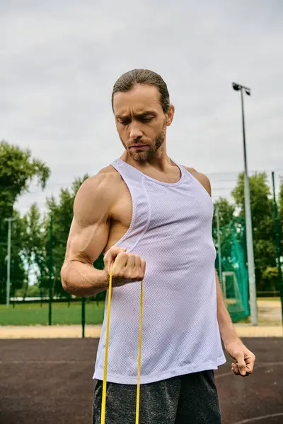 Un hombre determinado en ropa deportiva sostiene un elástico amarillo mientras hace ejercicio - foto de stock