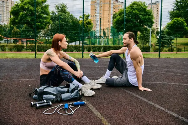 Ein Mann und eine Frau in Sportbekleidung trainieren gemeinsam auf einem Basketballfeld und zeigen Entschlossenheit und Motivation. — Stockfoto