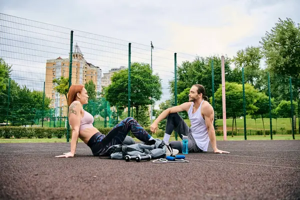 Um personal trainer dedicado guia um homem e uma mulher motivados no sportswear através do exercício no chão ao ar livre. — Fotografia de Stock
