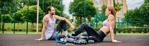 A woman in sportswear, after exercising, sit on the ground with personal trainer, showcasing determination and motivation. — Stock Photo