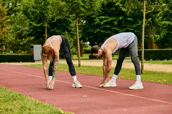 A woman in sportswear are exercising with a personal trainer on a track, showcasing determination and motivation. — Stock Photo