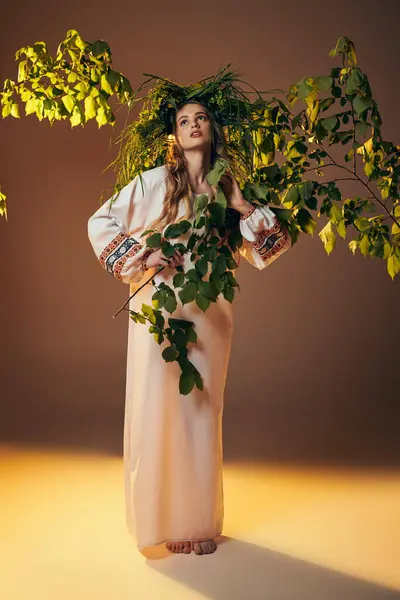 Jeune mavka en tenue traditionnelle, elle tient élégamment une plante dans un décor de studio féerique et d'inspiration fantastique.. — Photo de stock