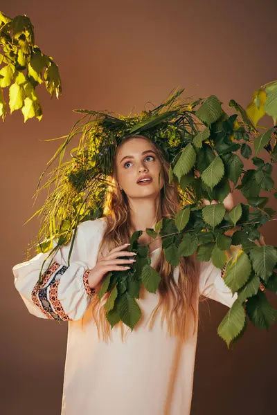 Junge Frau in traditionellem Outfit, geschmückt mit einem märchenhaften und fantasievollen Laubkranz in einem Atelier-Ambiente. — Stockfoto