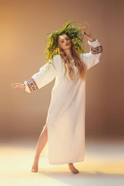 Молодая мавка в белом платье, украшенная зеленым венком, источает эфирное и мистическое присутствие в студии. — стоковое фото