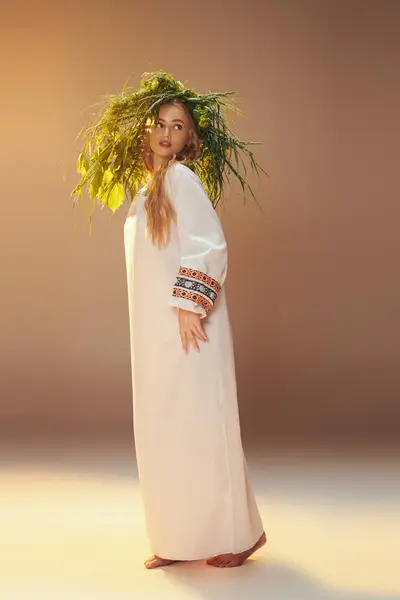 Une jeune mavka en robe blanche traditionnelle équilibre délicatement une plante sur sa tête dans un décor de studio féerique et fantastique. — Photo de stock