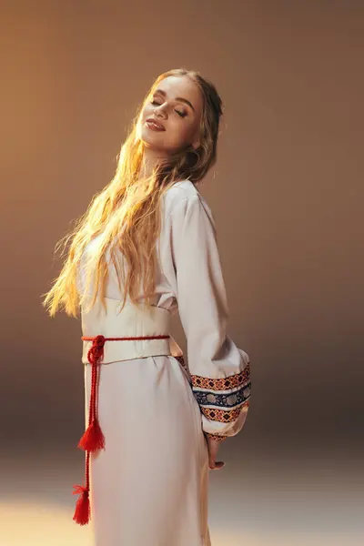 Une jeune femme envoûtante ornée d'une robe blanche aux pompons rouges complexes, aux vibrations féeriques et fantastiques dans un décor studio. — Photo de stock