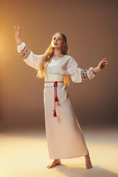 Молодая женщина в традиционном белом платье обнимает мир протянутыми руками в обстановке сказочно-фантастической студии. — стоковое фото