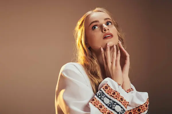 A young woman in a white shirt tenderly holds her hands to her face, embodying vulnerability and contemplation in a studio setting. — Stock Photo