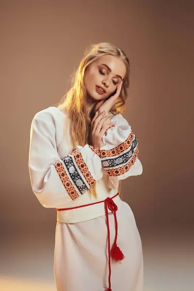 Une jeune mavka debout gracieusement dans une robe blanche ornée d'un pompon rouge vibrant, exsudant une aura de fée et de fantaisie. — Photo de stock