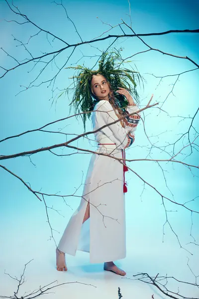 Um jovem mavka em um vestido branco graciosamente mantém um ramo delicado em um estúdio caprichoso. — Fotografia de Stock