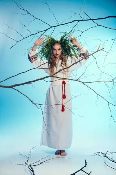 Un joven mavka, con un atuendo tradicional adornado, se levanta con gracia frente a un árbol místico con ramas. - foto de stock