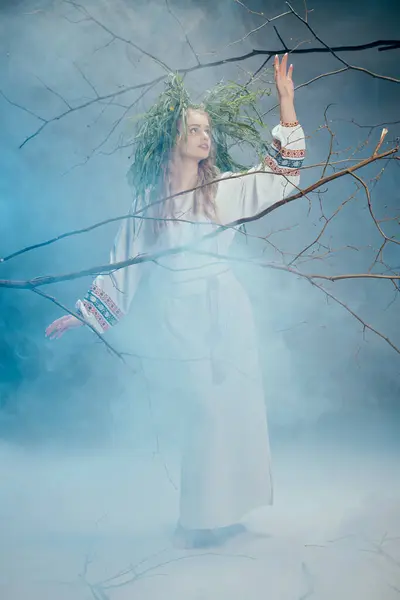 Uma jovem mulher em um vestido branco fica no meio do nevoeiro em uma floresta mística, exalando um ar de beleza etérea e mistério. — Fotografia de Stock