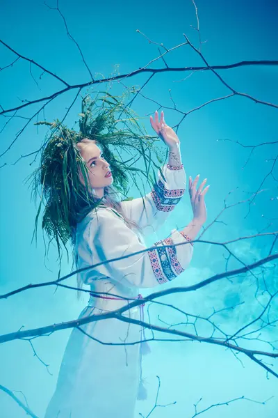 Um jovem mavka em traje tradicional com dreadlocks ornamentados de pé graciosamente na frente de uma árvore majestosa. — Fotografia de Stock