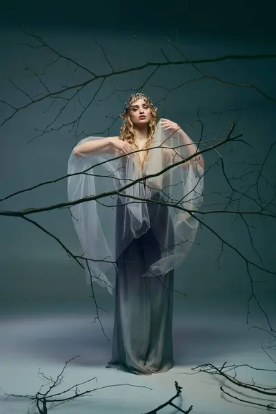 Uma jovem mulher em um vestido branco fluindo fica graciosamente na frente de um conjunto de ramos em um cenário de conto de fadas. — Fotografia de Stock