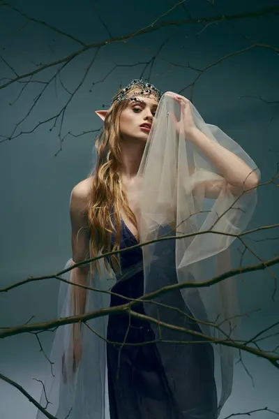Молодая женщина в платье, похожем на принцессу эльфов, украшенная вуалью, излучающая атмосферу фантазии и очарования в студии. — стоковое фото