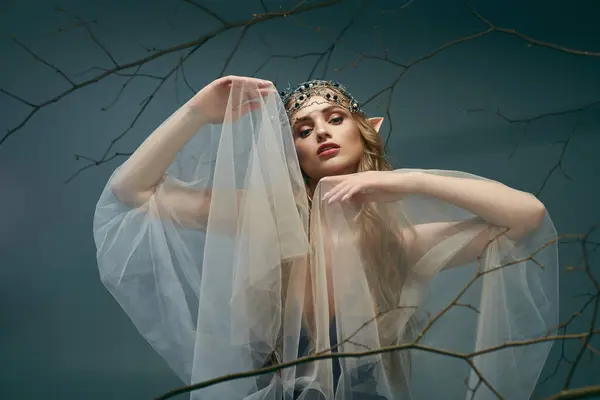 Uma jovem mulher, vestida como uma princesa duende, está com um véu adornando a cabeça em um estúdio místico. — Fotografia de Stock
