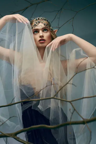 Uma jovem mulher, vestida como uma princesa duende, adorna um véu fluindo em sua cabeça em um estúdio. — Fotografia de Stock