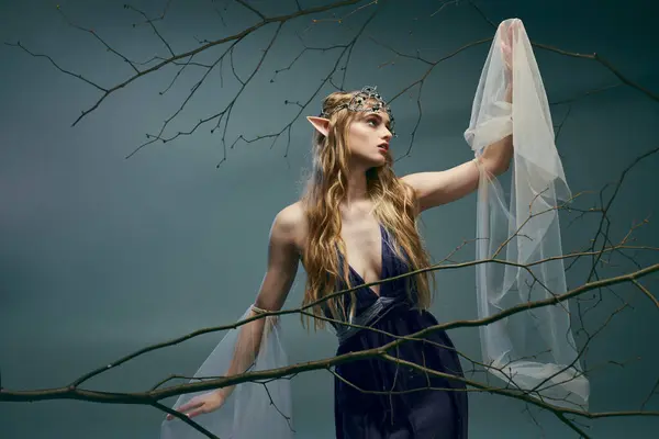 Молода жінка з вуаллю на голові витончено стоїть перед пишним деревом, втілюючи суть казкової принцеси. — стокове фото