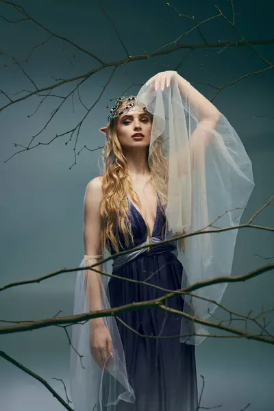 Молодая женщина с эфирным присутствием надевает красивое голубое платье и тонкую вуаль, воплощающую сущность выдуманной эльфийской принцессы. — стоковое фото